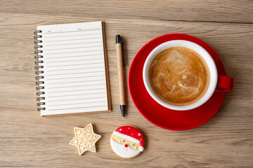 Blank notebook, black coffee cup, Christmas cookies and pen on wood table, Top view and copy space. Xmas, Happy New Year, Goals, Resolution, To do list, Strategy and Plan concept