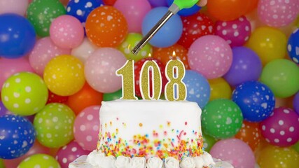 Cake with burning candles number 108. A tasty Birthday Cake on a bright festive background of colorful balloons.