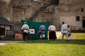 People in medieval clothes with bows on the territory of the castle