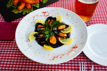 Closeup of deliciously appetizing steamed mussel with lemon and greens on a plate