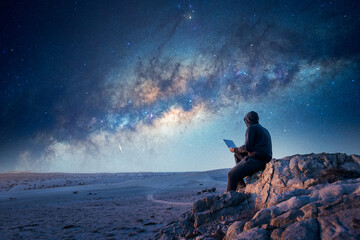 silhouette of a person sitting on the top of the mountain with a laptop and Milky Way background