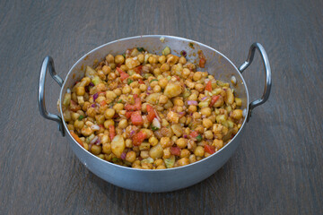 Indian delicious home made chaat of chickpeas, tomatoes, different fruits and masalas in aluminium wok