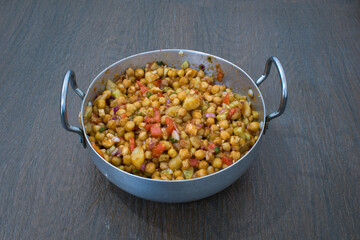 Indian delicious home made chaat of chickpeas, tomatoes, different fruits and masalas in aluminium wok