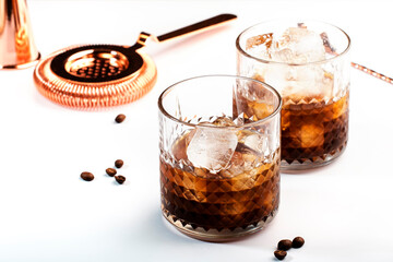 Black russian cocktail, trendy alcoholic drink with vodka, coffee liqueur and ice, white background, bar tools
