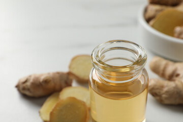Glass bottle of ginger essential oil on white table, closeup. Space for text
