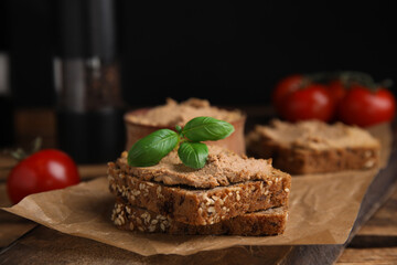 Fresh bread with delicious meat pate and basil served on wooden table, closeup