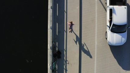 Person skateboarding on coastal asphalt sideway and road, top down aerial view