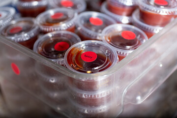 A closeup view of a tub full of customer ready condiment cups of sauce, seen at a local restaurant.