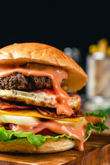 Fresh grilled homemade burgers with beef, tomato, fried egg, cheese and lettuce on rustic wooden background. fast food and junk food concept. fresh tasty burger on dark background.
