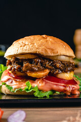 Fresh grilled homemade burgers with beef, tomato, fried egg, cheese and lettuce on rustic wooden background. fast food and junk food concept. fresh tasty burger on dark background.