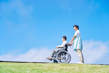 介護士と車椅子に乗る高齢者　屋外