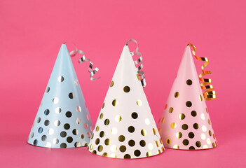 Bright party hats with streamers on pink background