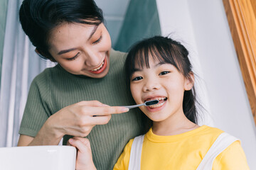 Mother and daughter brush their teeth together.