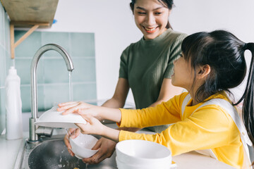 Mother and daughter wash the dishes together.