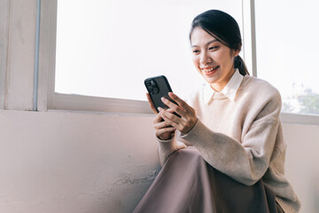Young Asian woman using smartphone at home