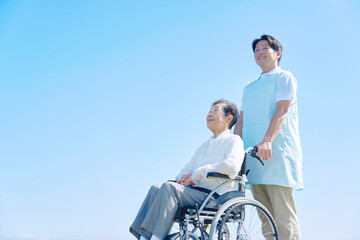 介護士と車椅子に乗る高齢者　屋外