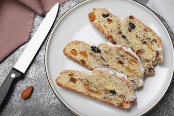 Traditional Christmas Stollen with icing sugar on grey table, flat lay