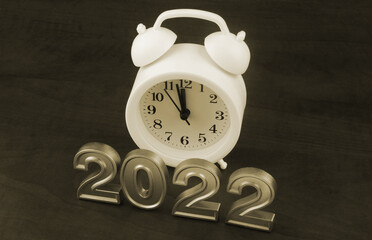 Alarm clock and numbers 2022 on wooden background