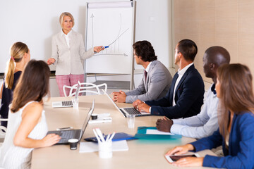 Successful mature woman sharing business ideas with colleagues in meeting room. Concept of teamwork