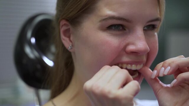 Woman uses aligner trainer. Attractive lady patient puts on comfortable aligners sitting in armchair in dentistry hospital office close view spbas