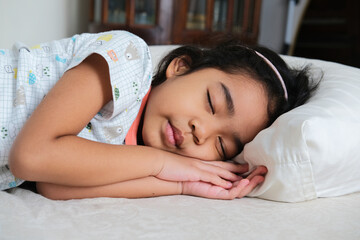 Asian little girl sleeping tight in her bed