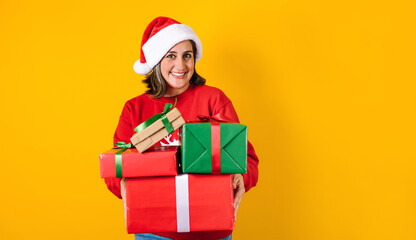 Portrait of Latin adult woman holding Christmas gift box on a yellow background in Mexico latin america
