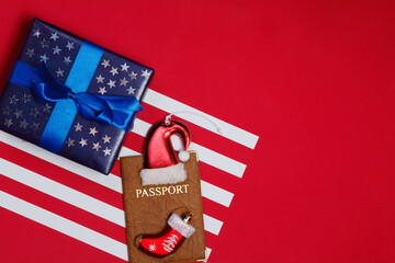 Fototapeta premium American flag composition with blue gift decorated with glittering stars and passport on red background. Merry christmas and happy new year concept..Space for text.