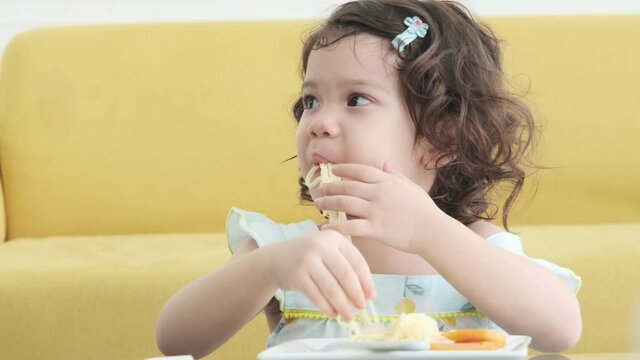 Little girl enjoy playing and eating spaghetti.