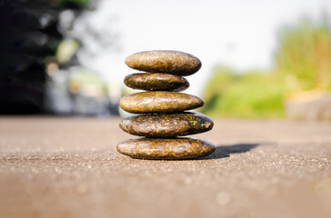 Stack pyramid stone zen pebbles nature on cement road with blur green leaves nature outdoor. meditation tranquil calm still balance relax of buddhism religion or aroma therapy spa massage set concept.