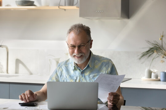 Happy Elder 60s Homeowner Man Getting Good News About Income, Money, Personal Finance, Doing Domestic Financial Work, Calculating Budget, Savings, Benefits, Paying Bills, Insurance Fees