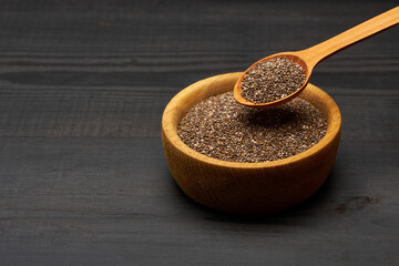 Bowl of organic natural chia seeds close-up on wooden background or table