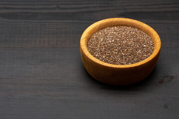 Bowl of organic natural chia seeds close-up on wooden background or table