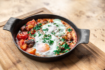 Close-up of traditional shakshuka in a frying pan on a wooden background.