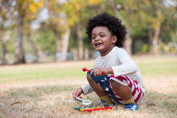 African American little boy playing toy in the park. Children with curly hair having fun outdoor. Black kid people enjoying outside