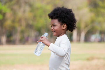 African American little girl drinking water while playing  in the park