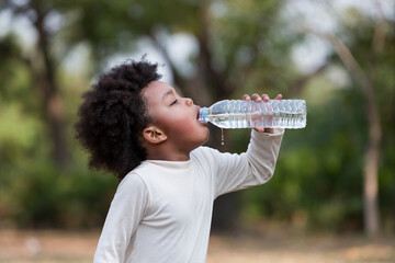 African American little girl drinking water while playing  in the park