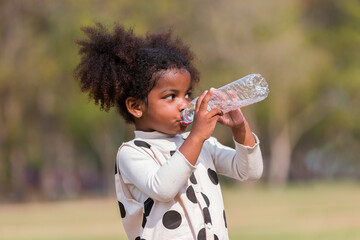 African American little girl drinking water while playing  in the park