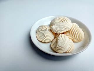 Spritz cookies, or custard cookies or roti semprit in Indonesian. Cookies shaped like a clam shell. Placed inside white small plate.