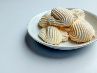 Spritz cookies, or custard cookies or roti semprit in Indonesian. Cookies shaped like a clam shell. Placed inside white small plate.