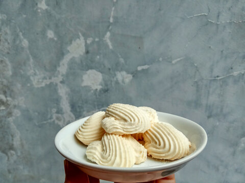 Spritz cookies, or custard cookies or roti semprit in Indonesian. Cookies shaped like a clam shell. Placed inside white small plate.