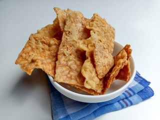 Keripik tempe or tempeh crackers. Inside a white bowl, isolated in white background
