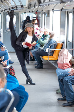 Very flexible woman reading book in the subway standing in gymnastic split. Concept of healthy lifestyle, flexibility and yoga