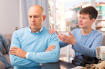 Obraz premium Portrait of unhappy adult man turned away from his son teenager