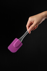 Hand holding cake spatula on black background