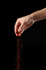 Hand holding cayenne pepper on black background