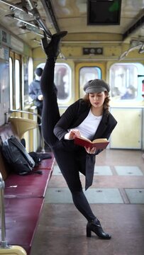 Very flexible woman reading book in the subway car standing in the gymnastic split. Concept of healthy lifestyle and education