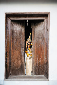 A young woman is wearing a chada that is a Khon costume. by the window