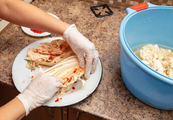 A woman is salting cabbage in Korean in the kitchen.