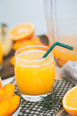 persimmon juice in a glass And there are orange slices and a blender all around.