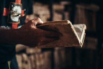 Senior man hands holding an old book in a library
